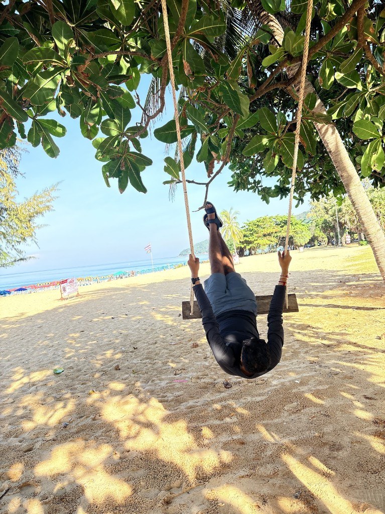 Ronak hanging upside down on a beach swing